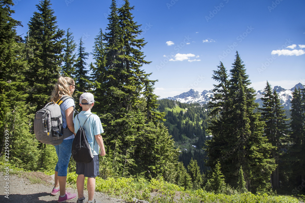 A mother and son hiking together on a beautiful scenic mountain trail at Mount Rainier National Park in Washington USA
