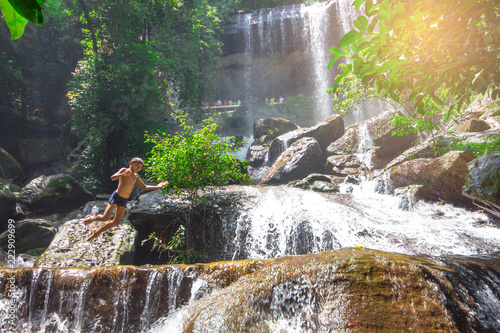 Boy is jumping into a waterfall in forest at Soo Da Cave Roi et Thailand