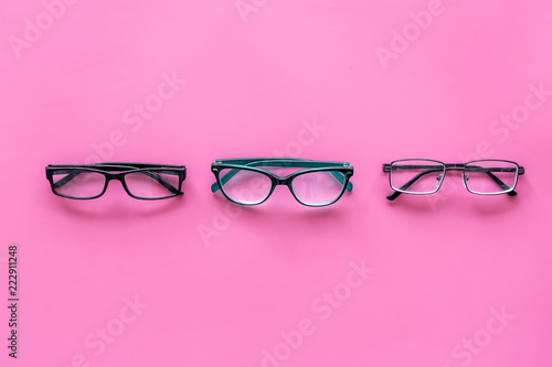 Glasses with transparent optical lenses on pink background top view space for text