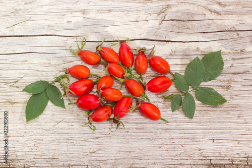 Red rose hips with leaves on an old wooden surface