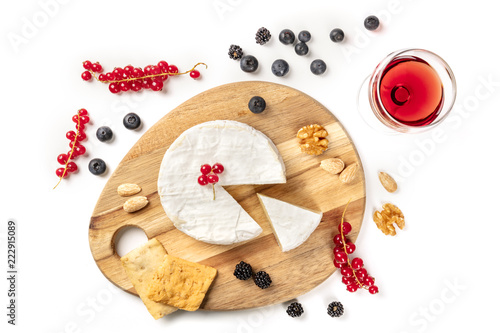 An overhead photo of Camembert cheese with a glass of red wine, fruits and nuts, shot from above on a white background with copy space