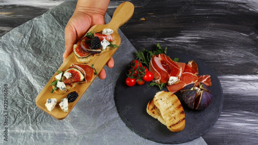 Appetizers table with antipasti snacks. Cheese and meat, fruits and berries variety board in the hand is chef's cheese. Top view, flat lay, copy space