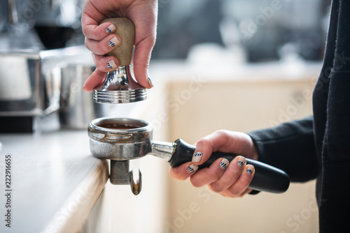 Photos Barista presses ground coffee using tamper.