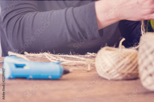 Woman decorating a bottle from wine with an ecological twine. Rustic style, handmade craft. Gift for christmas and other celebrations. Crafting process. Selective focus