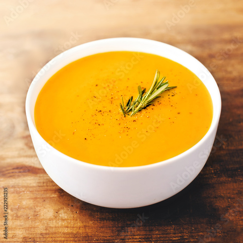 Squash Soup with Rosemary on rustic wooden table.  Autumn Pumpkin cream-soup with croutons. Top view. Copy space.