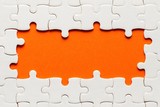 White details of puzzle on orange background and place for inscription