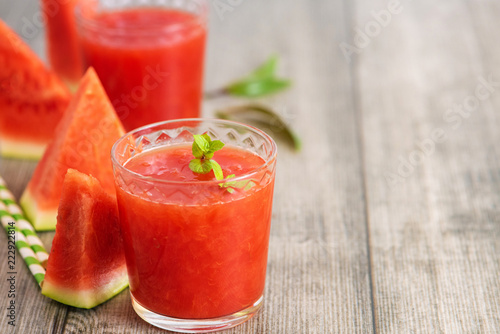 Watermelon smoothie in jars with fresh watermelon slices on gray wooden background. Copy space