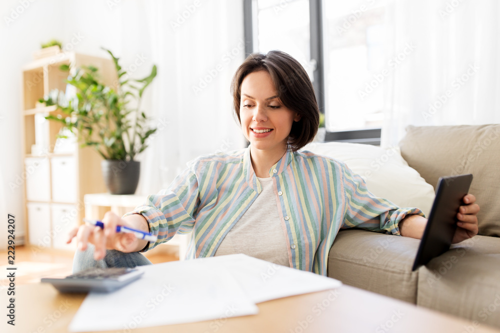 business, savings, finances and people concept - woman with tablet pc, papers and calculator at home business, savings, finances and people concept - woman with tablet pc, papers and calculator at home