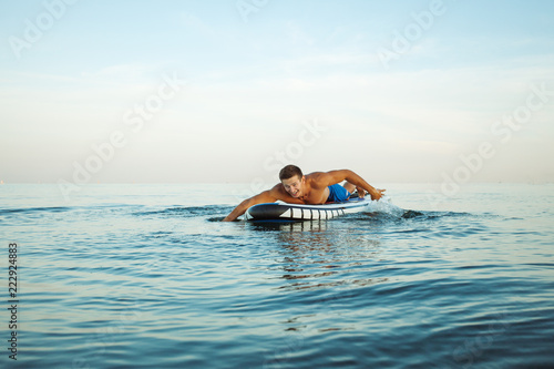 Man doing paddle surf at sunrise