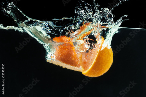 Orange falls into the water and making splashes