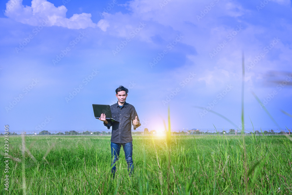 Man holding computer notebook standing green field sky could background Man holding computer notebook standing green field sky could background