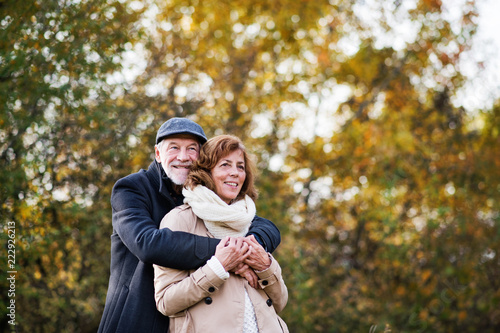 Senior couple standing in an autumn nature, hugging. © Halfpoint