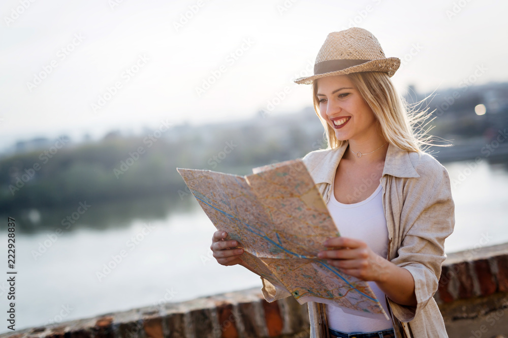 Fototapeta premium Happy tourist woman on vacation with map visiting city