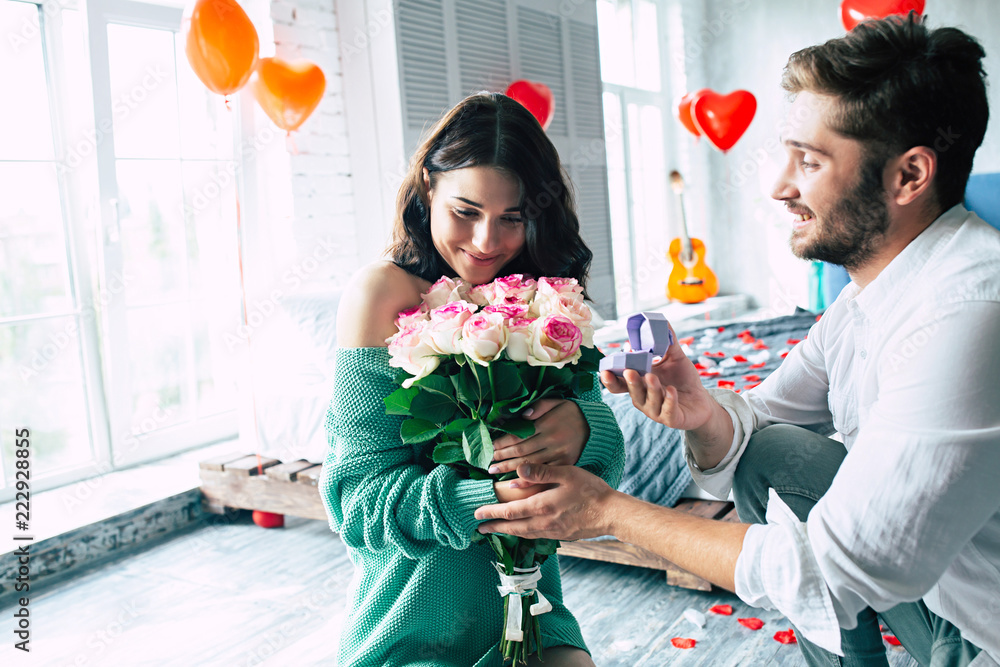 Young handsome man makes a proposal to his beautiful girlfriend to marry him in a beautiful bedroom with a romantic background. Husband and wife Young handsome man makes a proposal to his beautiful girlfriend to marry him in a beautiful bedroom with a romantic background. Husband and wife