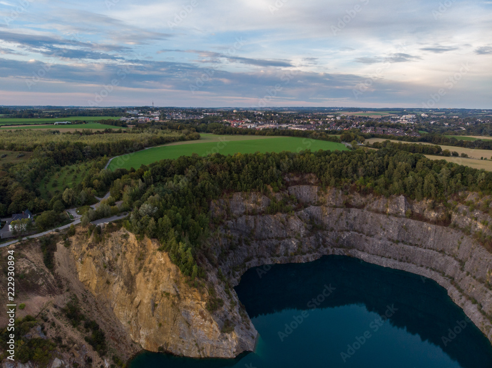 (Luftaufnahme, Drohne) Panorama mit blauem Kratersee im Steinbruch im Vordergrund