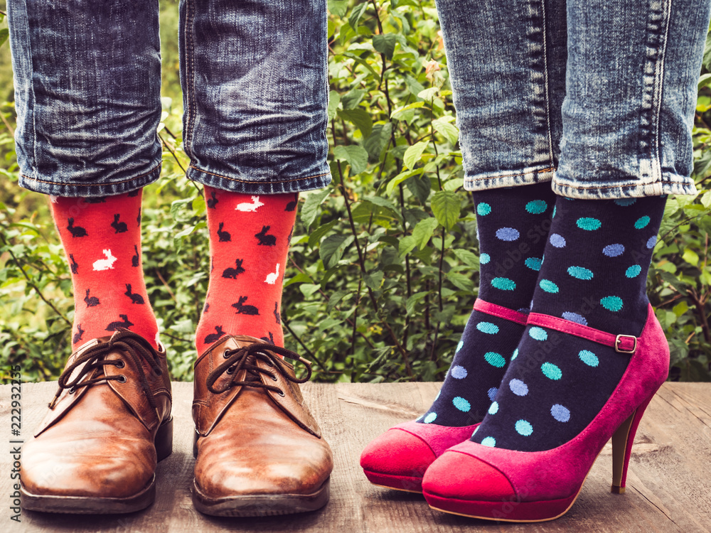 Men's and women's feet in stylish shoes, bright, colorful socks on the wooden terrace on the background of green trees. Lifestyle, fashion, beauty, fun Men's and women's feet in stylish shoes, bright, colorful socks on the wooden terrace on the background of green trees. Lifestyle, fashion, beauty, fun