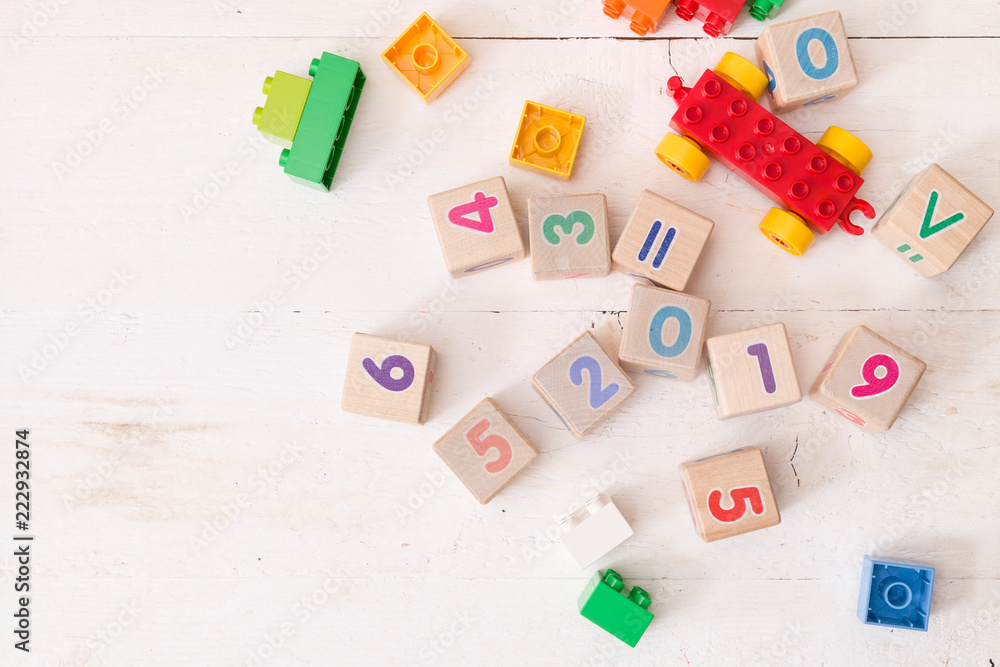 Top view on wooden cubes with numbers 2019 and multi-color toy bricks on old white wooden background. Toys in the table. Early learning and development. Top view on wooden cubes with numbers 2019 and multi-color toy bricks on old white wooden background. Toys in the table. Early learning and development.