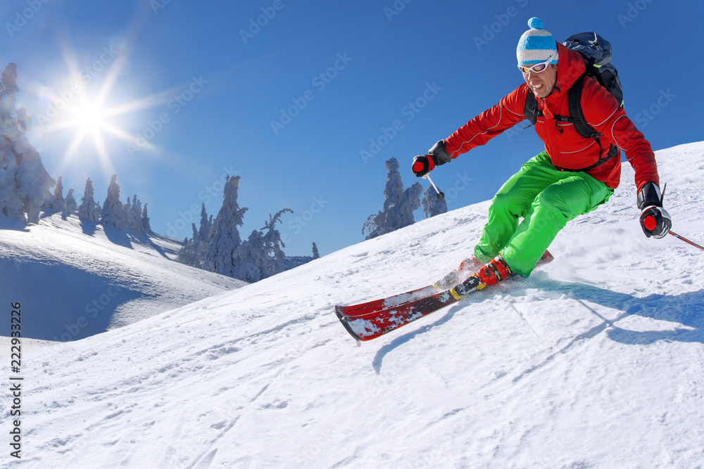 Skier skiing downhill in high mountains against blue sky