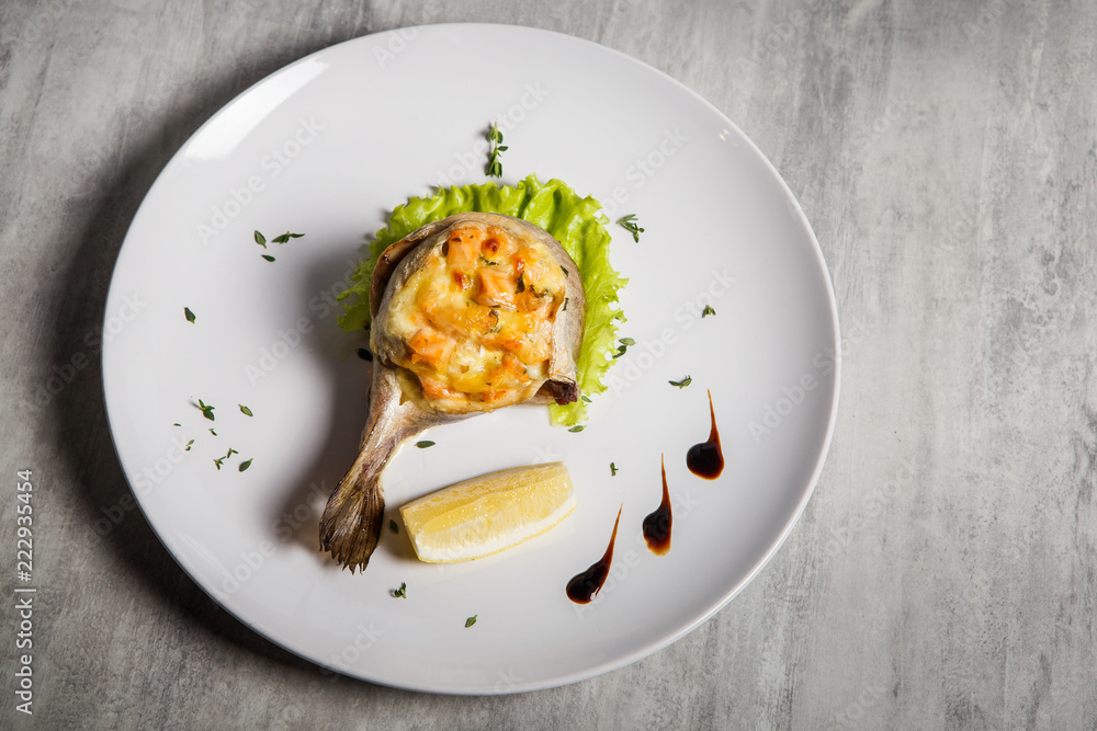 top view on baked trout with stuffing, salad, lemon and sauce
