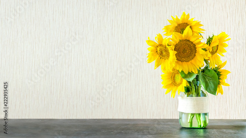 Bright yellow big sunflowers in glass vase on dark table on light texture background. Mockup banner with sunflower bouquet with copy space.