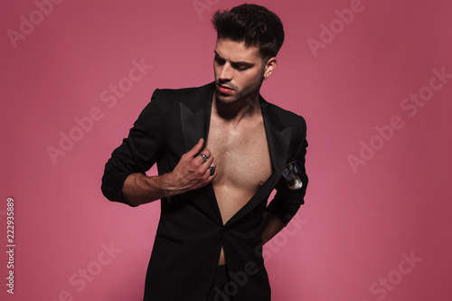 seductive man holding tux collar and looking down to side