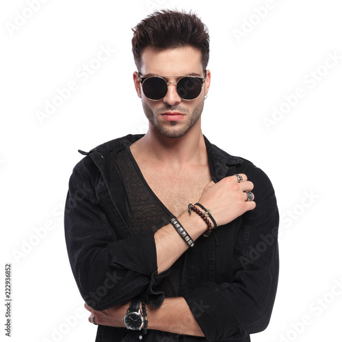 portrait of young man with sunglasses holding his collar