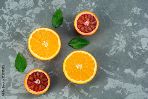 Oranges fruits composition with green leaves and slice on concrete background, top view © Vladyslav Bashutskyy