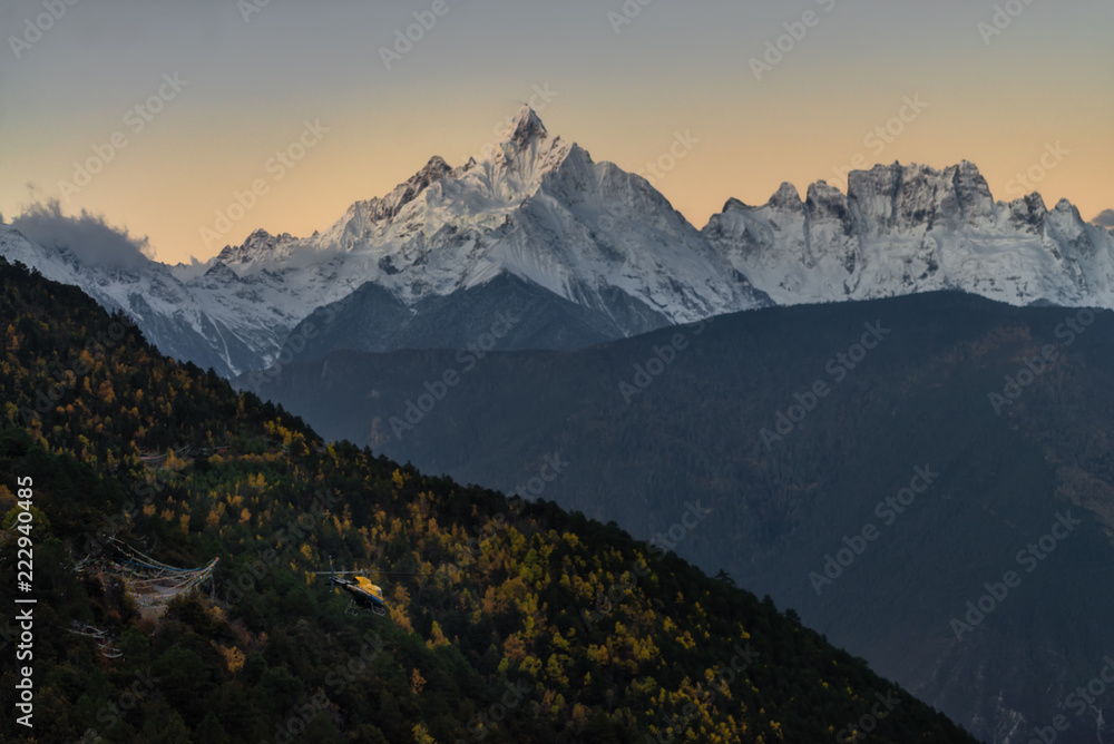 Meili snow mountain range with Mianzimu peak and tourist helicopter during sunrise in Deqing, Yunan province, China