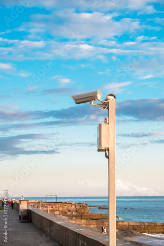 street video surveillance of public order, video cameras on a pole against the blue sky with clouds