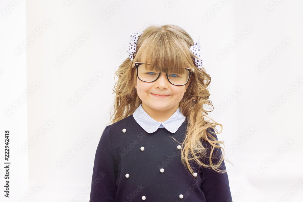 Little cheerful blue-eyed girl first-class with winded hair with bantikami and glasses in school uniform with a briefcase on September 1 is at the school on a white background Little cheerful blue-eyed girl first-class with winded hair with bantikami and glasses in school uniform with a briefcase on September 1 is at the school on a white background