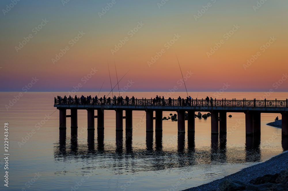 pier at sunset with fisherman