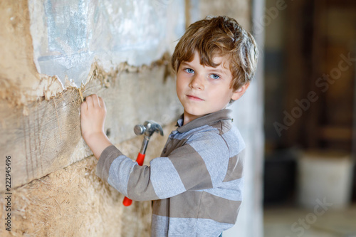 Little kid boy helping with toy tools on construciton site.