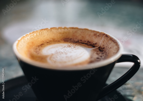 Cappuccino coffee with latte art on top in ceramic cup on vintage grunge wood table background for morning or refreshment. Soft focus.