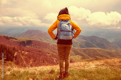 Girl with rucksack on the top of the hilly landscape.