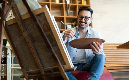 Portrait Of Male Artist Working On Painting In Studio