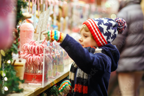 Little cute kid boy buying sweets from a cancy stand on Christmas market photo