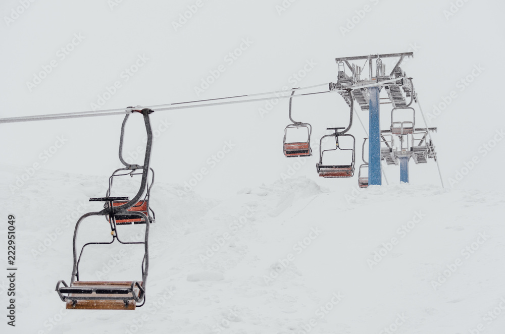 Chairs of a ski lift heading into the fog Chairs of a ski lift heading into the fog