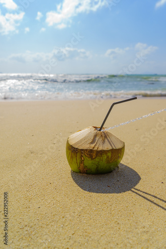 Coconut with drinking straw on beach