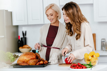 beautiful adult daughter and senior mother cooking thanksgiving dinner together