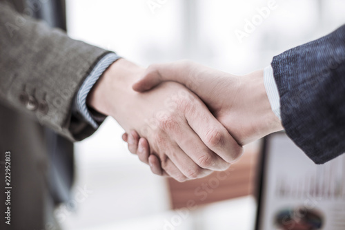 concept of a reliable partnership: a handshake of business partners on blurred light background