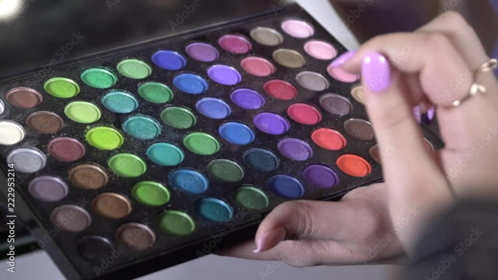 color matching to create a make-up. a woman chooses a shade of color with her hand on a pallet with shadows color matching to create a make-up. a woman chooses a shade of color with her hand on a pallet with shadows