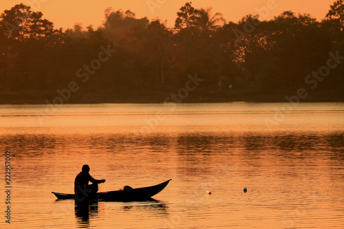 Silhouette of a fisherman working on the lake during the sunset 
