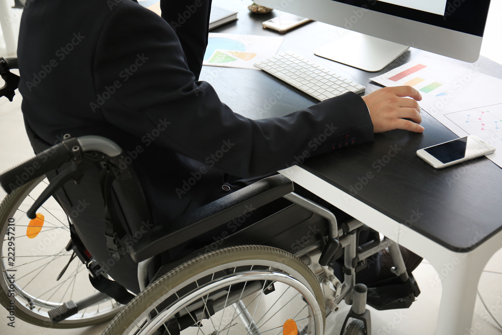 Businessman in wheelchair working with computer in office Businessman in wheelchair working with computer in office