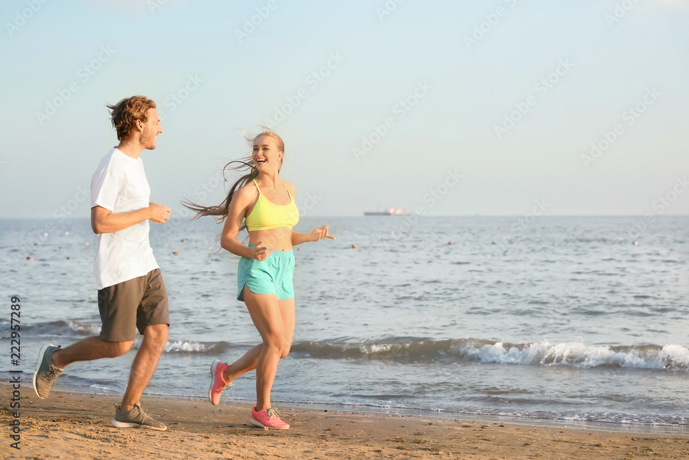 Sporty young couple running on sea beach