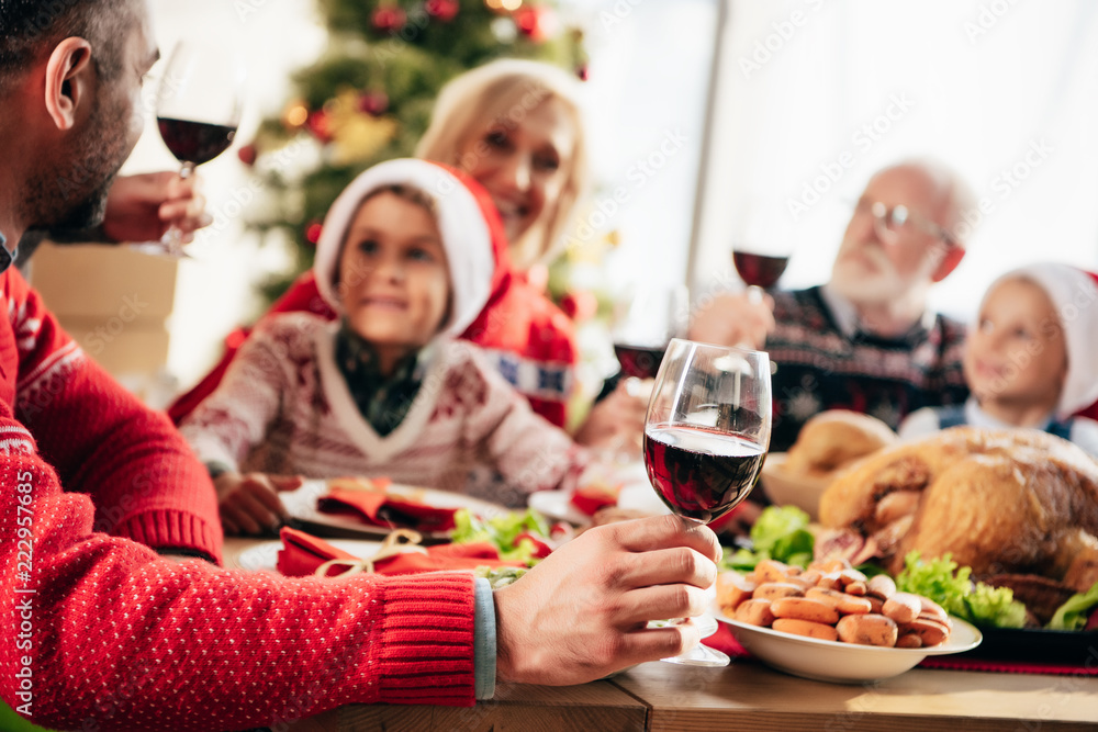 partial view of man with wine sitting at table with family while having christmas dinner