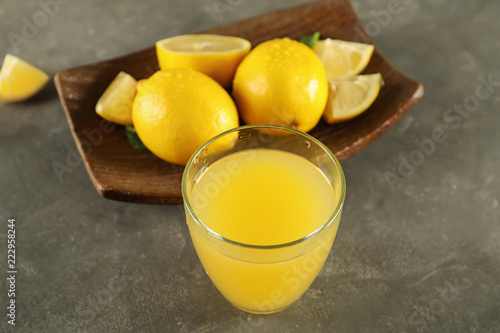 Glass of fresh lemon juice on grey table
