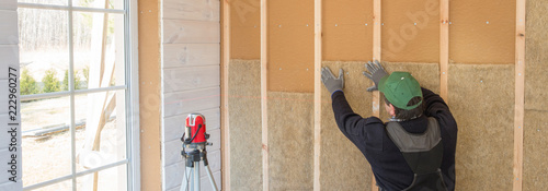 фотографія Construction worker thermally insulating eco-wood frame house with wood fiber plates and heat-isolating natural hemp material