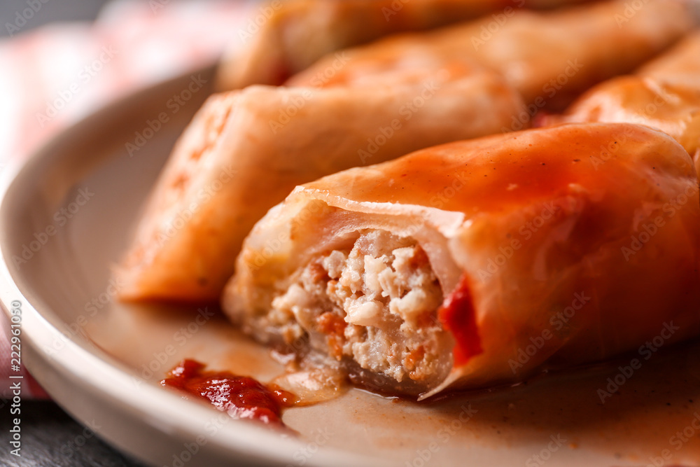 Stuffed cabbage leaves in tomato sauce on plate, closeup