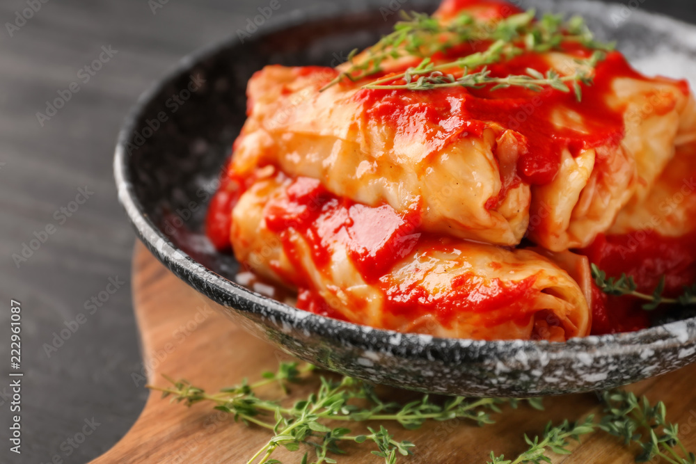 Plate with stuffed cabbage leaves in tomato sauce on wooden board, closeup Plate with stuffed cabbage leaves in tomato sauce on wooden board, closeup