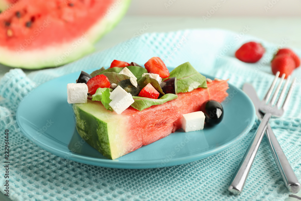 Plate with slice of watermelon and tasty salad on table Plate with slice of watermelon and tasty salad on table